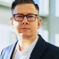 Portrait of a man with glasses in a dark blazer